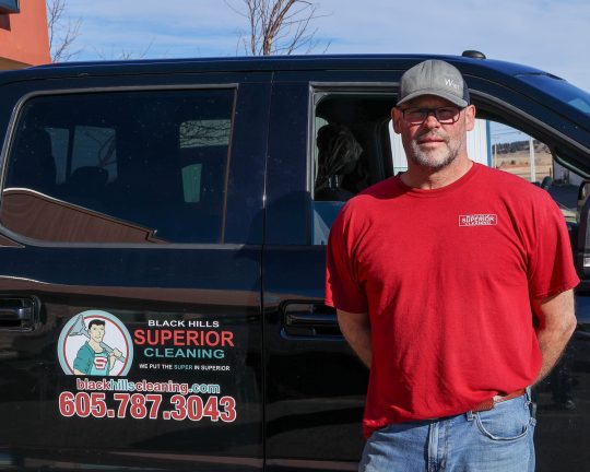 Jon from Black Hills Superior Cleaning Carpet Cleaning expert Jon standing in front of his truck. The Black Hills Carpet Cleaning logo can be seen on the rear door.