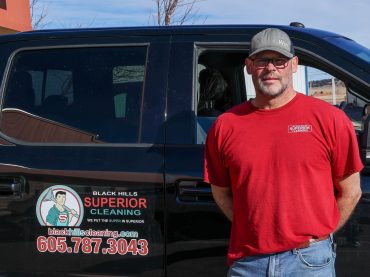 Carpet Cleaning expert Jon standing in front of his truck. The Black Hills Carpet Cleaning logo can be seen on the rear door.