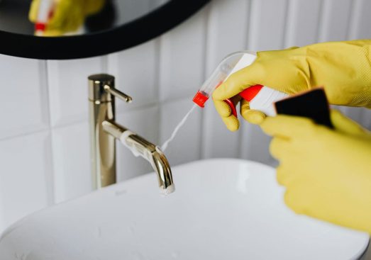 Professional Cleaner Spraying a Sink with Non-Toxic Cleaners