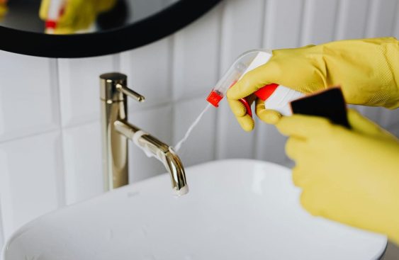 Professional Cleaner Spraying a Sink with Non-Toxic Cleaners