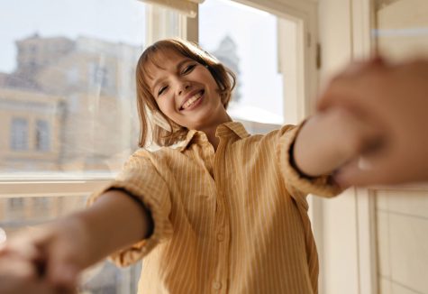 Woman happy in a brighter home after window cleaning A woman takes a selfie in front of freshly cleaned windows leading to a brighter home and mood.